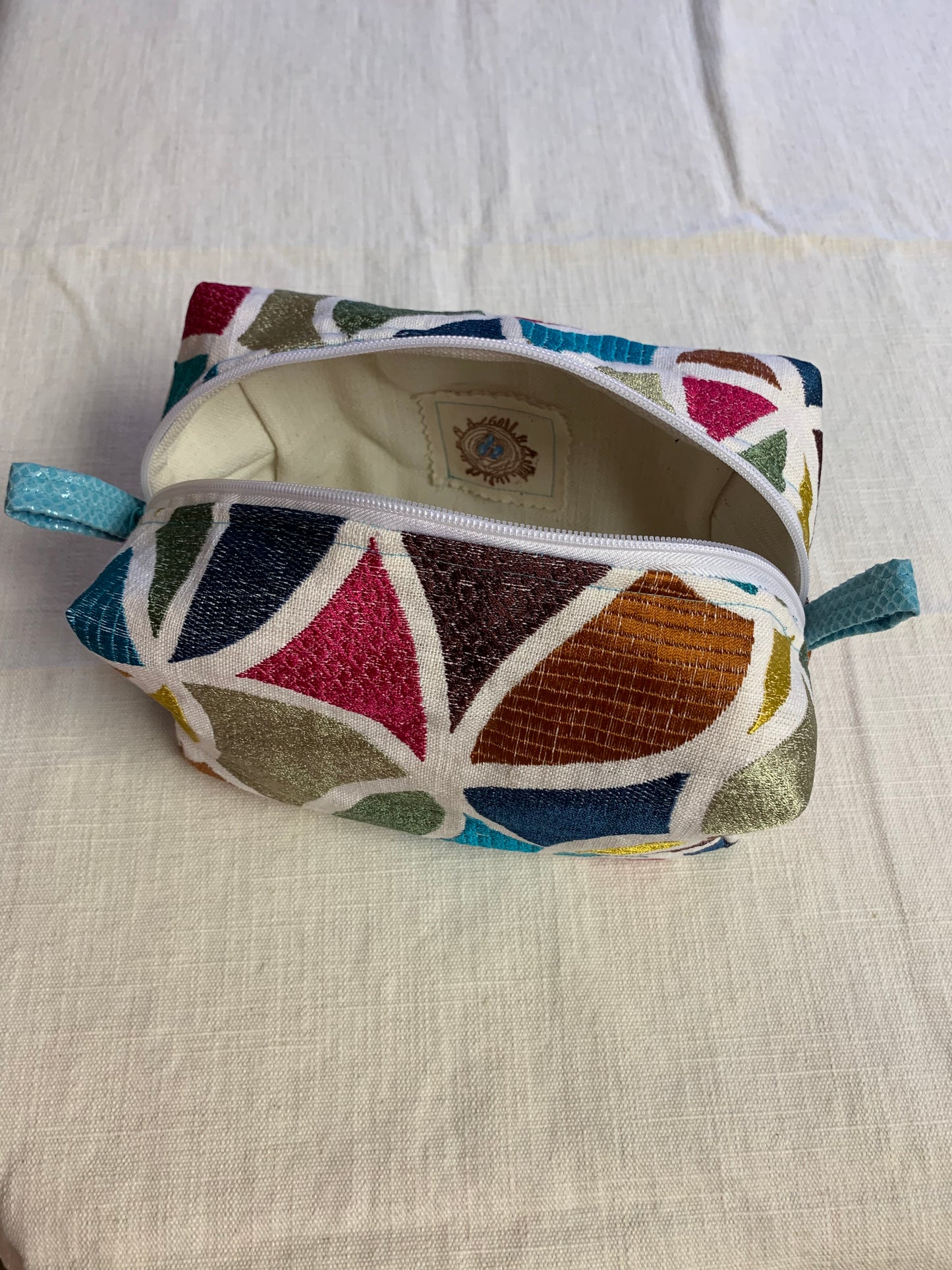Nest all of your essential make up and toiletries in a piece of art curated from a rare selection of textiles. Designed to spark excitement to self care. Geometric jewelled stained glass textile print. 