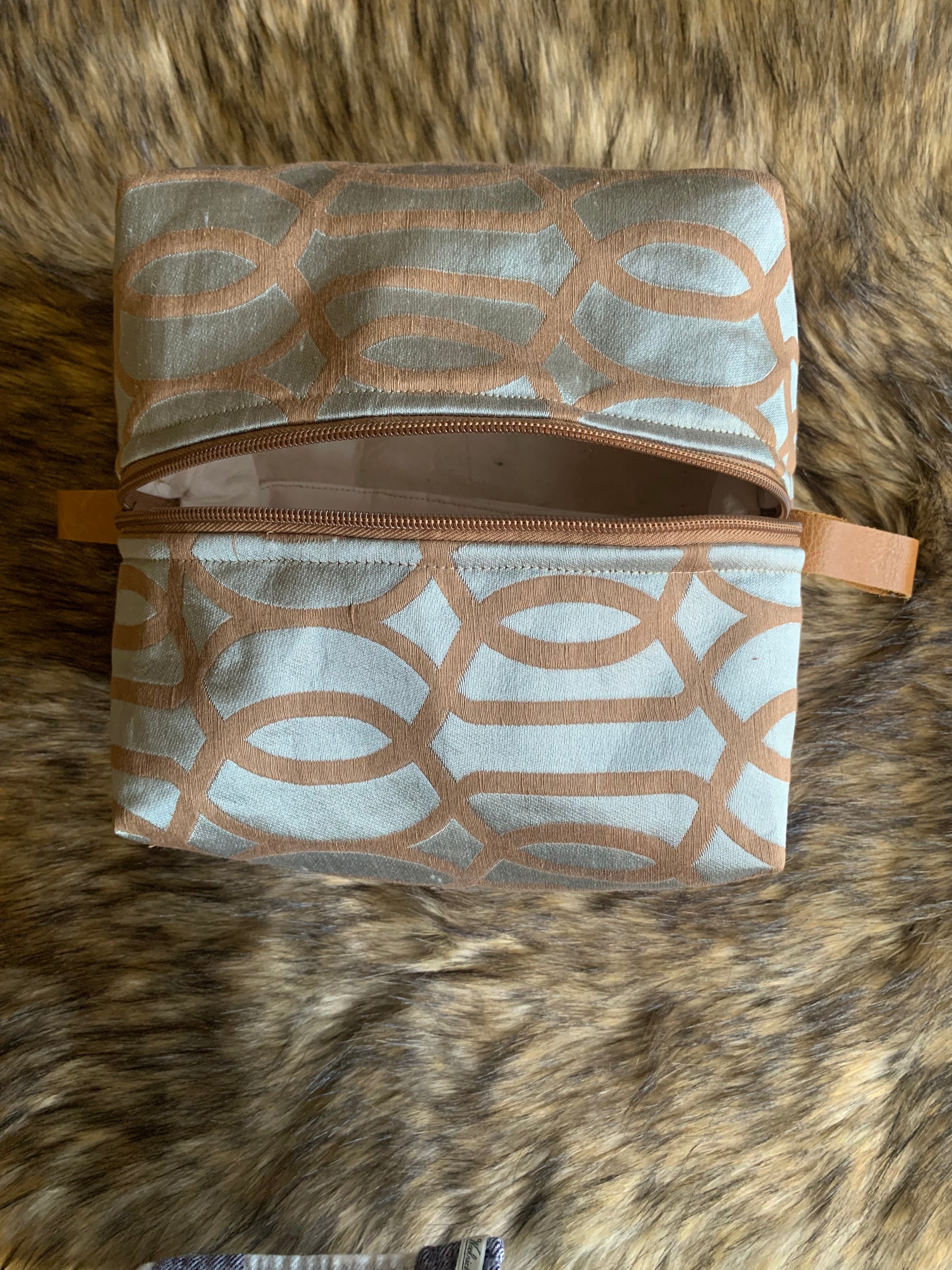 Nesting essentials travel cosmetic bag.
Soft teal shimmering Deco silk fabric with an overlayed flat embroidery in tan colour. Tan zipper and tan leather thumb handles. Square shape for larger collection. 