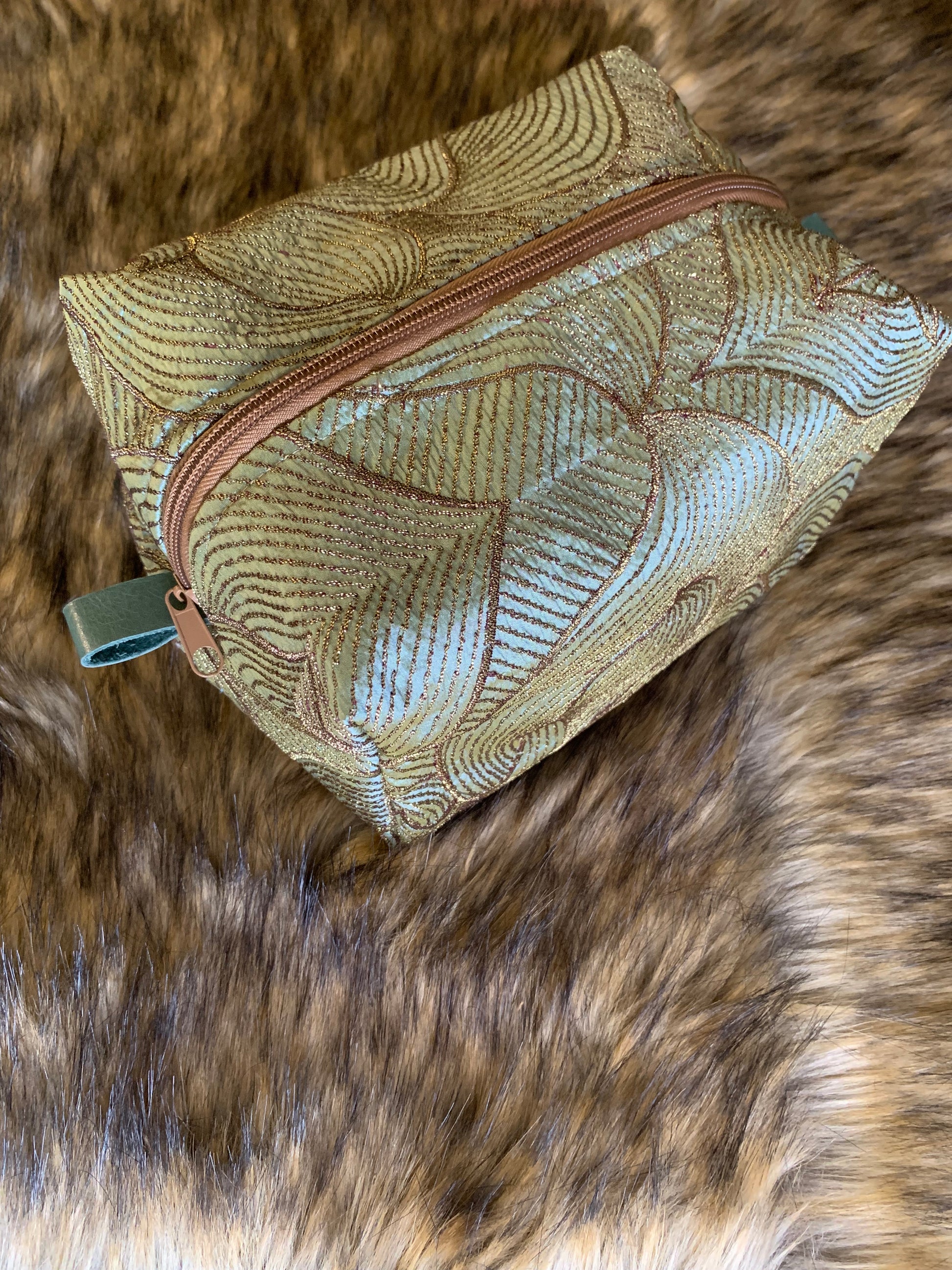 For those that covet exquisite fabric this one is so unique, it inspires a conversation at first sight. A iridescent soft teal adorned with stylized leaves embroidered in a antique bronze thread. Nest all of your precious essentials together with elegance. Each Nesting Essentials is fully lined and padded with unbleached 100% cotton. Hand wash as needed. Tan zipper and teal leather thumb handles. 