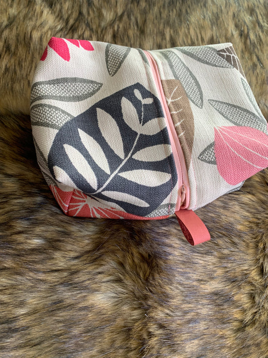Travel cosmetic box bag in a large print stylized tropical floral greys and coral. Pink zipper and pink thumb handles. Zipper is centered vertically for larger opening. 100% cotton lining. 